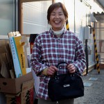 Женщина (63 года) держит в руках чёрную сумку, которую ей вместе с другими повседневными мелочами привезла старшая сестра из префектуры Аомори. «Я почувствовала, насколько крепки наши узы», - сказала она. Рикудзэнтаката, префектура Иватэ. 12-е апреля 2011 г.