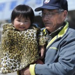 Пожилой мужчина держит на руках свою внучку. «Надеюсь, мне, по крайней мере, удастся найти семейный алтарь», - сказал он. Мияко, префектура Иватэ. 10-е апреля 2011 г.
