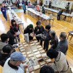 Выжившие ищут семейные фотографии в общественном спортзале. Мияко, префектура Иватэ. 10-е марта 2012 г. К годовщине землетрясения в спортзале выставили множество фотографий и личных вещей, найденных после катастрофы