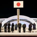 Жители пострадавшей префектуры Фукусима кланяются в память жертв Великого восточнояпонского землетрясения и цунами на мемориальной церемонии в Национальном театре в Токио. 11-е марта 2012 г.